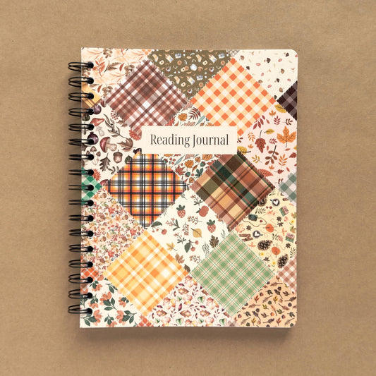 Spiral-bound softcover reading journal notebook with autumn patchwork cover design on a brown background
