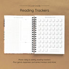 Open spiral-bound hardcover reading journal notebook showing daily and weekly reading trackers on a brown background