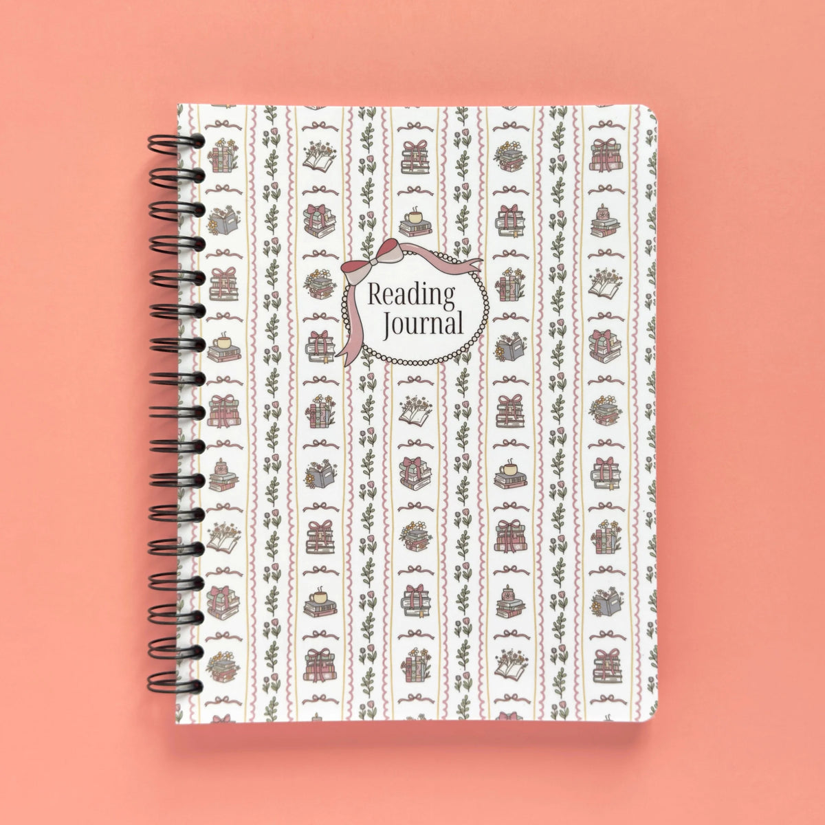 Spiral-bound softcover reading journal notebook with books and bows coquette cover design on a peach background