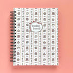 Spiral-bound hardcover reading journal notebook with books and bows coquette cover design on a peach background