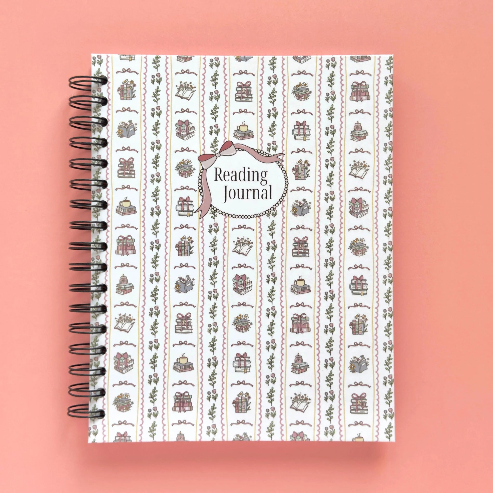 Spiral-bound hardcover reading journal notebook with books and bows coquette cover design on a peach background
