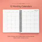 Open spiral-bound softcover reading journal notebook showing monthly calendar pages on a peach background