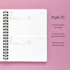 Open spiral-bound softcover reading journal notebook showing review template option Style 2C featuring two book reviews per page and ten review lines plus book details per review, displayed on a lavender background