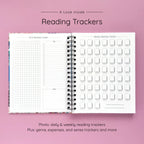 Open spiral-bound hardcover reading journal notebook showing daily and weekly reading trackers on a lavender background