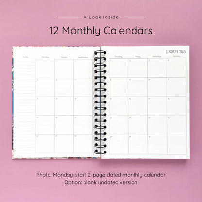Open spiral-bound hardcover reading journal notebook showing monthly calendar pages on a lavender background