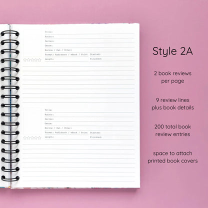 Open spiral-bound hardcover reading journal notebook showing review template option Style 2A featuring two book reviews per page and nine review lines plus book details per review with space to attach printed book covers, displayed on a lavender background