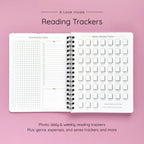 Open spiral-bound softcover reading journal notebook showing daily and weekly reading trackers on a lavender background