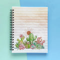 Spiral-bound hardcover lined notebook with cactus and succulent cover design on a teal and blue background