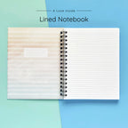 Open spiral-bound hardcover lined notebook showing lined notes pages on a teal and blue background