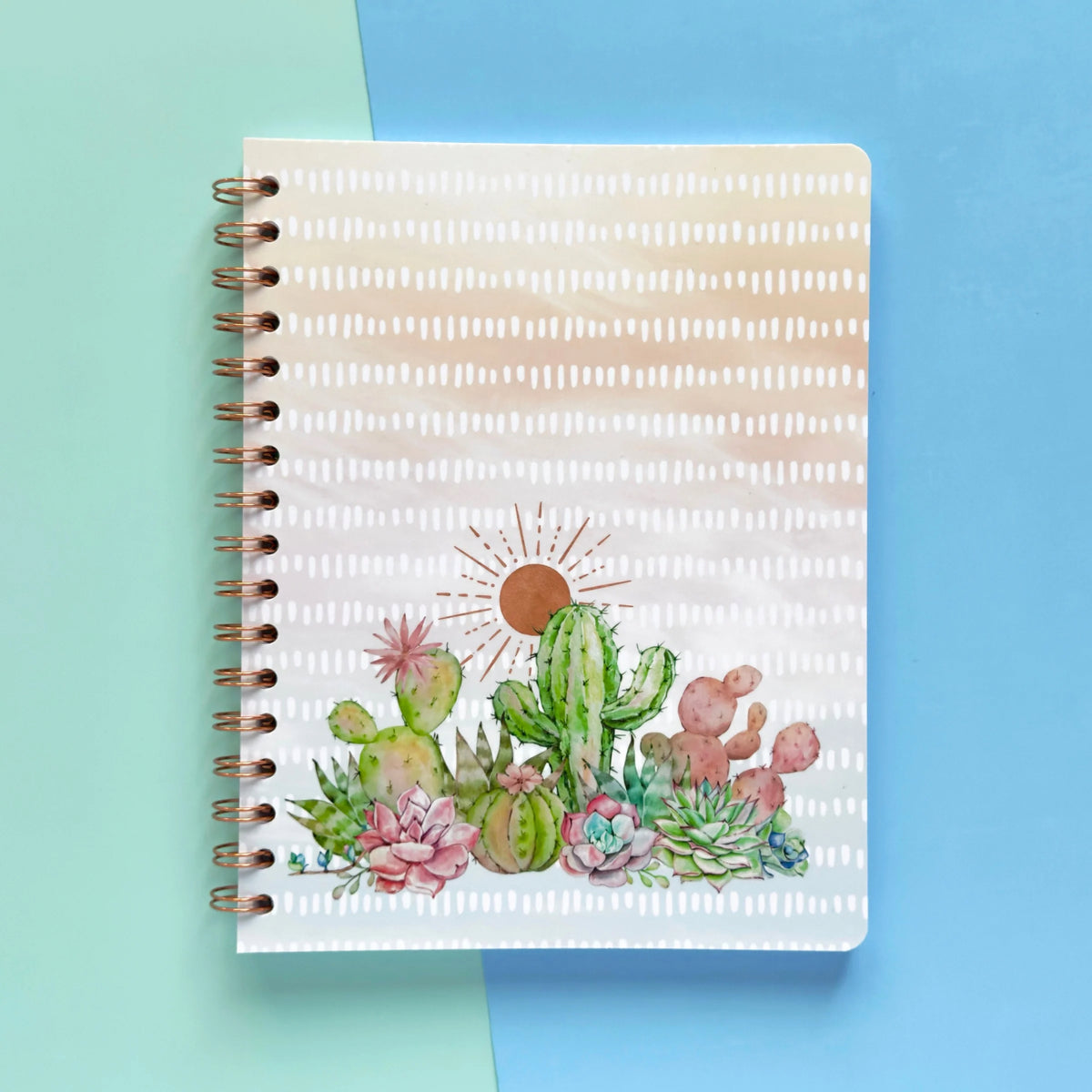 Spiral-bound softcover lined notebook with cactus and succulent cover design on a teal and blue background, featuring rose gold wire binding