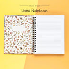 Open spiral-bound hardcover lined notebook showing lined notes pages on a yellow and orange background