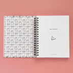 Spiral-bound hardcover reading journal flip through video with books and bows coquette cover design on peach background